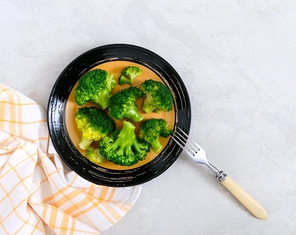 a plate of broccoli with a fork with a tablecloth next to it. supporting liver health. Top foods for liver support